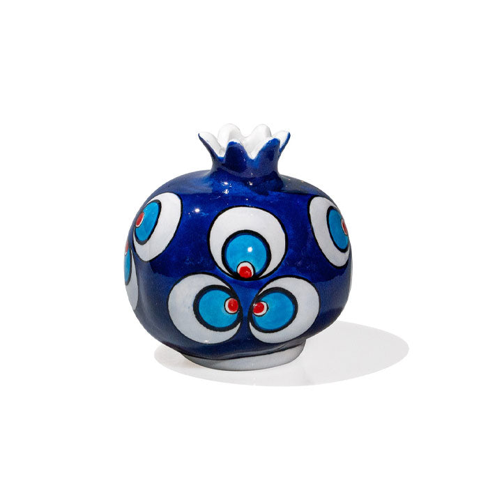 A blue and white ceramic pomegranate with a geometric pattern and a floral design at the top.